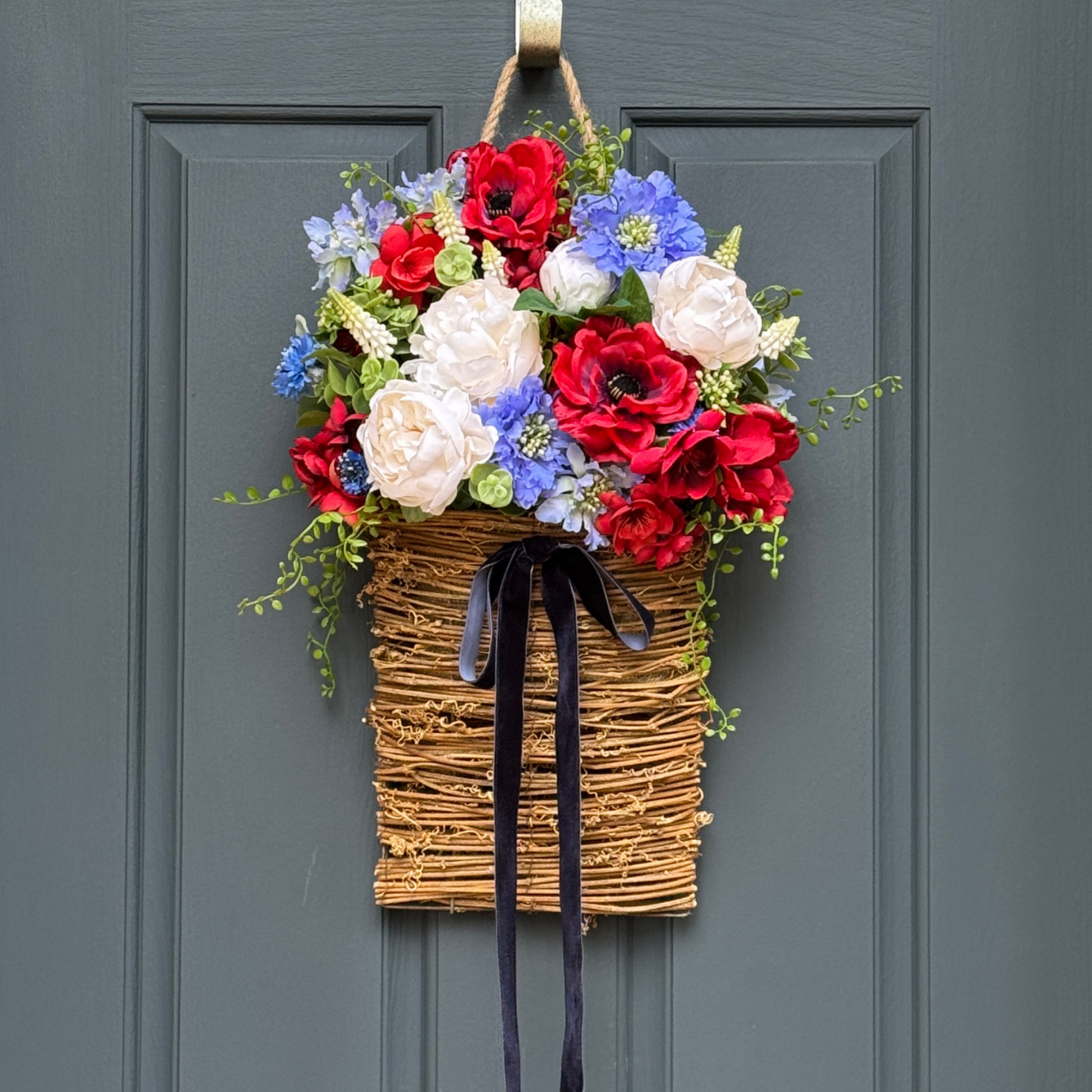 Floral wreath with red, white, and blue flowers on a gray door