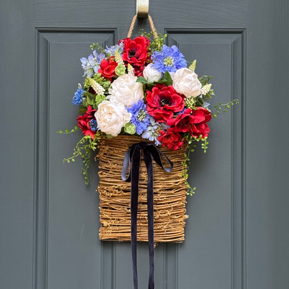 Floral wreath with red, white, and blue flowers on a gray door