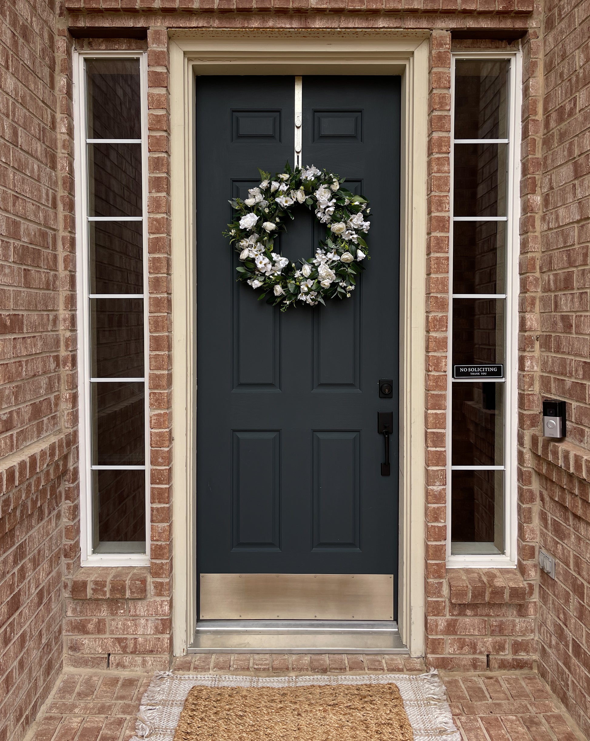 Dark blue front door with a white wreath on a brick house