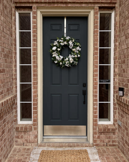 Dark blue front door with a white wreath on a brick house