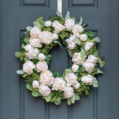 White peony and eucalyptus wreath with soft blooms, buds, and greenery on an 18-inch grapevine base for elegant front door or indoor décor.