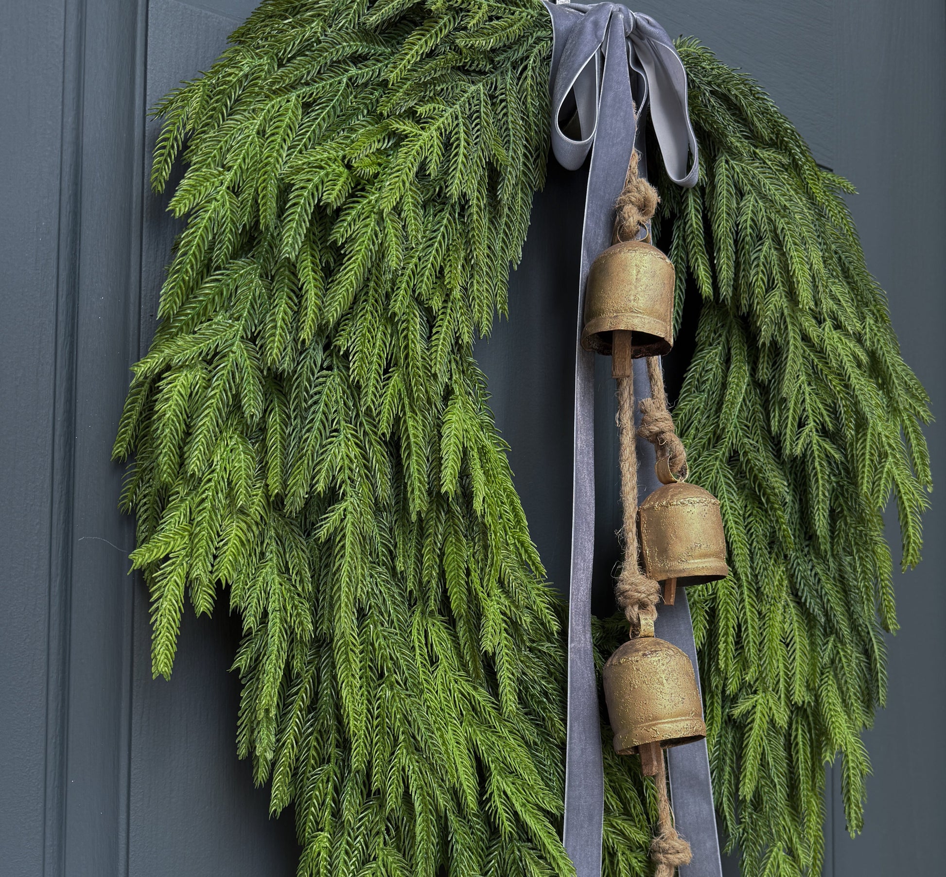 Green wreath with gold bells and a gray ribbon on a door