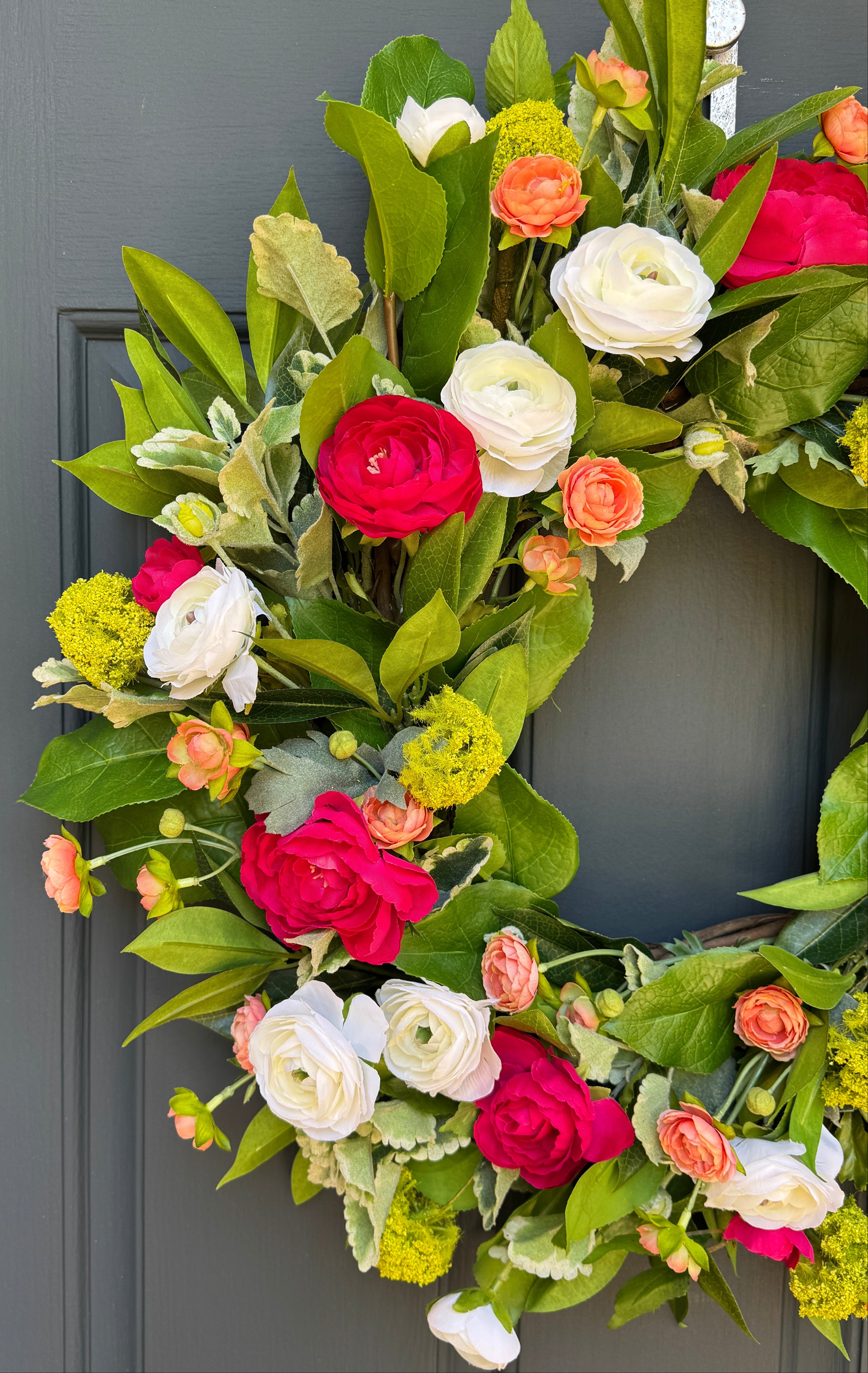 Floral wreath with white and bright pink flowers on a gray door