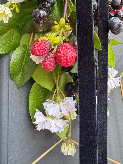 Artificial flowers and berries on a star wreath with a gray background