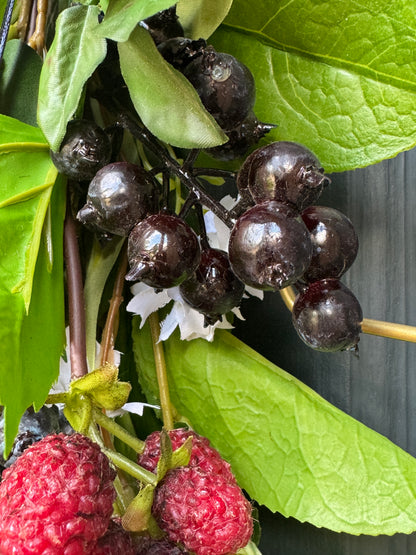 Close-up of dark berries and red berries with green leaves on a dark background