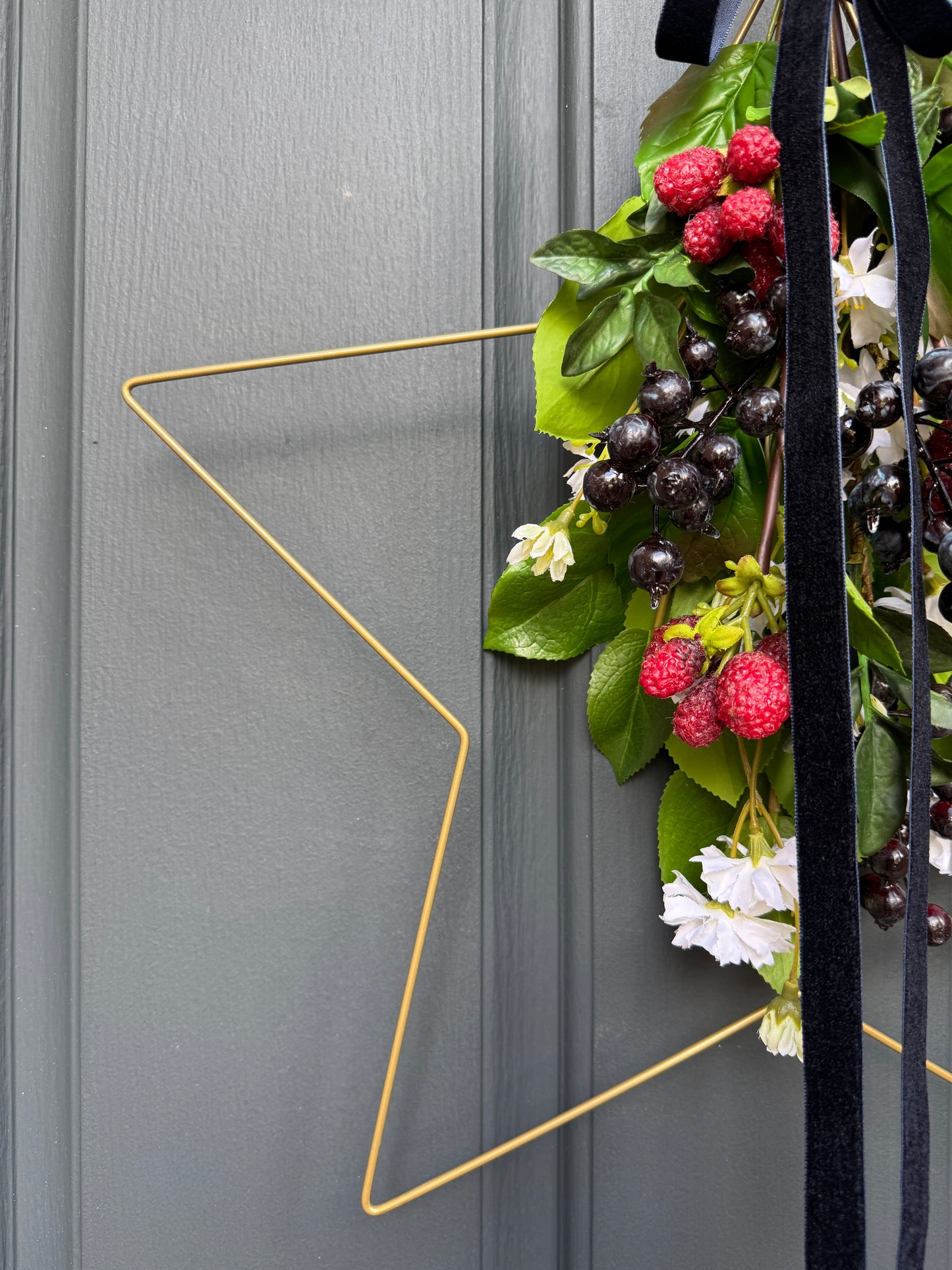 Decorative star wreath with berries and leaves on a door with geometric gold star decoration.