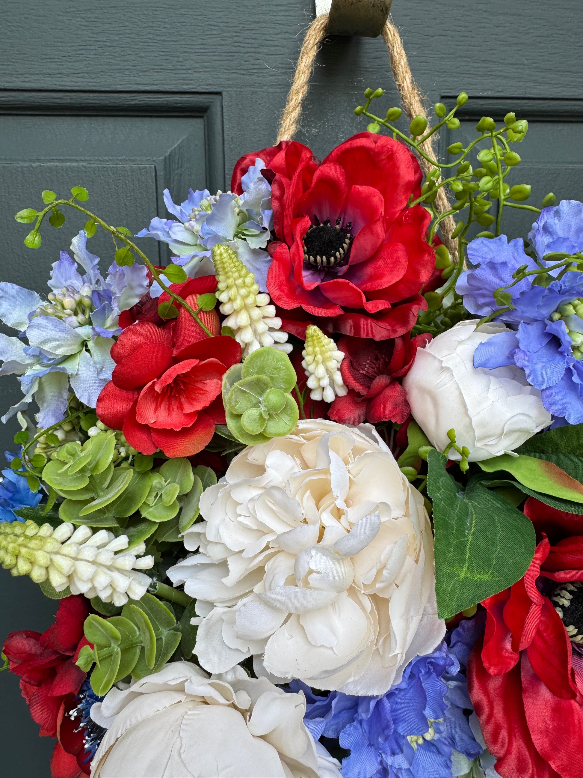 Colorful floral wreath with red, blue, and white flowers on a door.