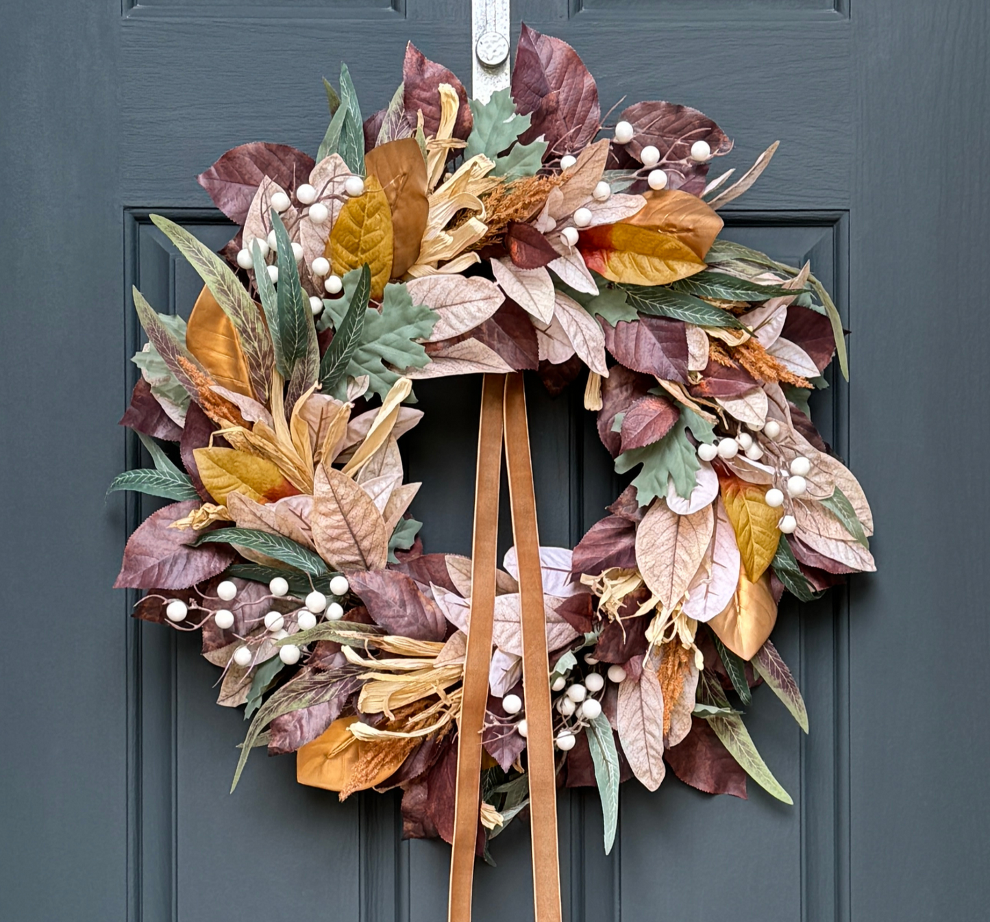 Autumn leaf wreath with brown ribbons on a blue door