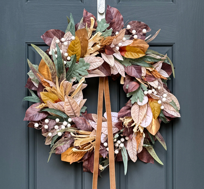 Autumn leaf wreath with brown ribbons on a blue door
