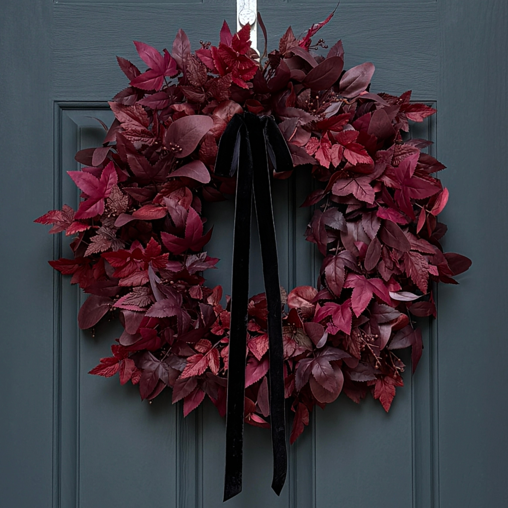 Red leaf wreath with a black ribbon on a gray door