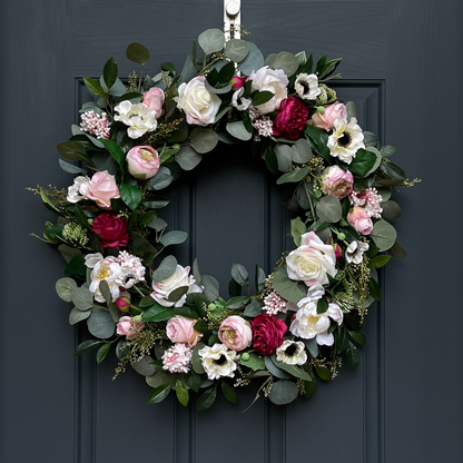 Pink and cream floral wreath with peonies, roses, ranunculus, anemones, and eucalyptus on a grapevine base for summer front door décor.