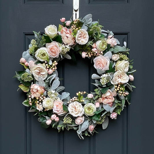 Brighten your front door with this light pink and cream peony, rose, and lilac wreath, perfect for the spring season! This high-end wreath has been handcrafted on a grapevine base and is trimmed with light pink & cream peonies, roses, and lilacs, accented with greenery including lambs and ruscus, and pink/green berries.