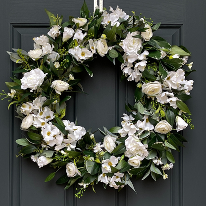 Handcrafted by Darling Grape / Emily Allen. This high-end, artificial spring front door wreath has been handcrafted on a grapevine base and is filled with dogwood blossoms, ranunculus, and lisianthus and accented with mini floral sprays and green berries. Florals are nestled in various greenery, including osmanthus, pittosporum, and eucalyptus.