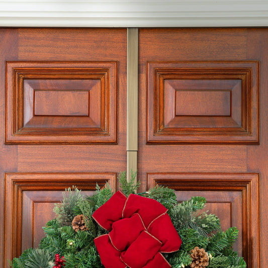 Wooden door with an antique bronze wreath hanger, featuring a wreath with a red bow