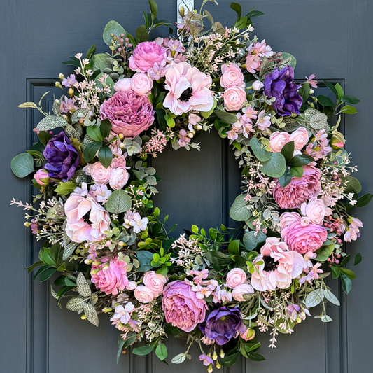 Floral wreath with pink and purple flowers on a dark blue door