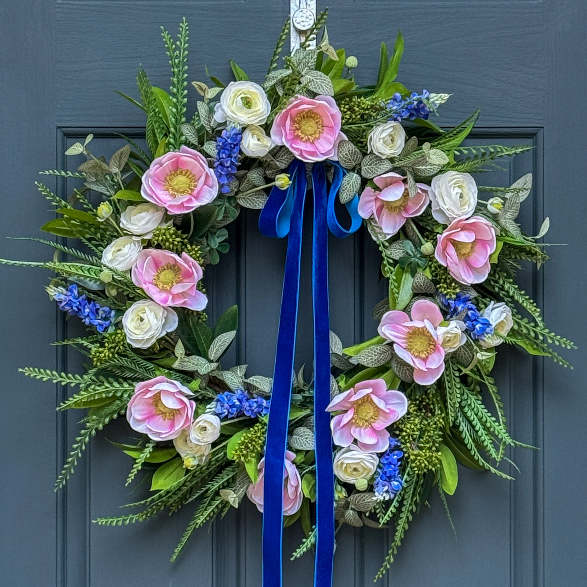 Floral wreath with pink, white, and blue flowers on a blue door